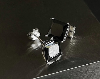 May include: A pair of silver stud earrings with black square-shaped gemstones.