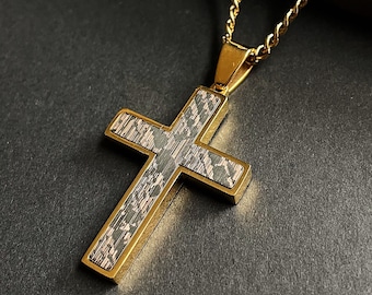 Op de afbeelding: Goudkleurige kruisvormige hangerketting. Het kruis heeft een patroon in het midden met goudkleurige randen en hangt aan een bijpassende gouden ketting. Het ontwerp is geplaatst tegen een donkere achtergrond.