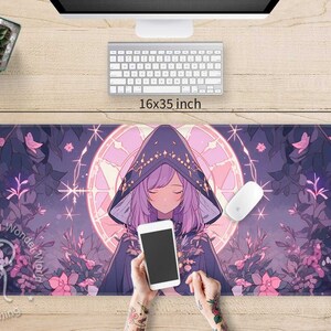 May include: A purple and pink anime-style mouse mat featuring a girl wearing a hooded cloak and holding a smartphone. The mouse mat has a floral design and a circular pattern with stars. The text "Raging Wonder World" is visible on the mouse mat.