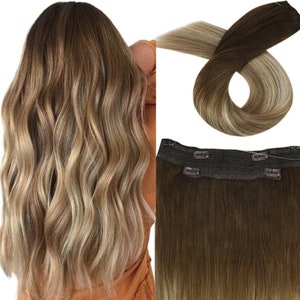May include: A set of clip-in hair extensions with a dark brown base and lighter blonde highlights. The extensions have a seamless weft and are designed to blend naturally with your hair.