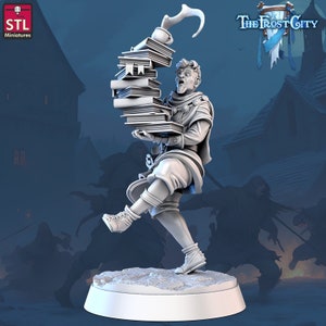 May include: A white 3D-printed miniature figure from "The Frost City" series, balancing a tall stack of books. The character has an animated expression. The base is circular. The figure is set against a blurred background.