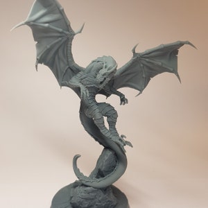 May include: A gray, detailed dragon figurine with wings spread wide, perched on a rock base. The dragon's tail curls around the rock, creating a dynamic pose.