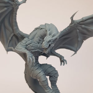 May include: A gray, detailed dragon figurine with wings spread wide, poised in mid-flight. The dragon has a fierce expression with sharp teeth and claws.