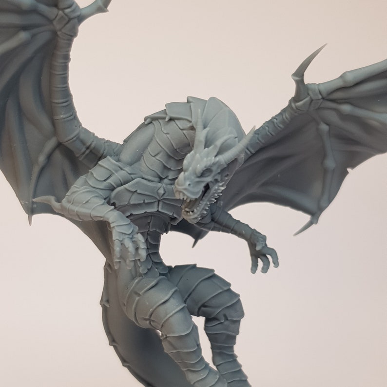May include: A gray, detailed dragon figurine with wings spread wide, poised in mid-flight. The dragon has a fierce expression with sharp teeth and claws.