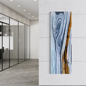 May include: Abstract wall art featuring a blue, white, and gold swirling pattern. The artwork is framed and hanging on a white wall.