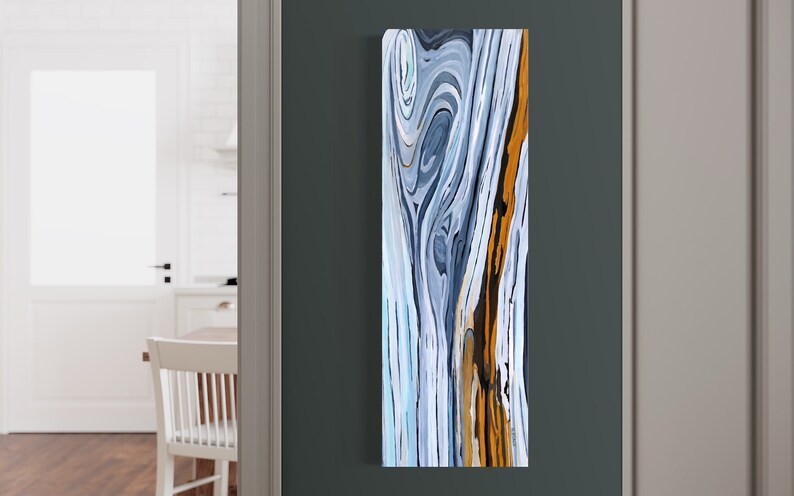 May include: Abstract painting with swirling lines in shades of blue, white, and brown. The painting has a vertical format and is framed.