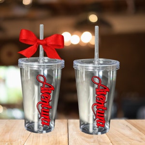 May include: Two clear plastic tumblers with red straws and the word "aventura" written in red on the side. One tumbler has a red bow on the straw.