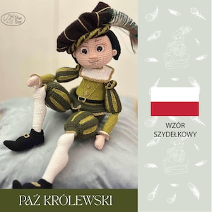 May include: A handmade crochet doll in a green and gold outfit with a feathered hat. The doll has a white collar and black shoes. The text "PAZ KRÓLEWSKI" is at the bottom of the image.