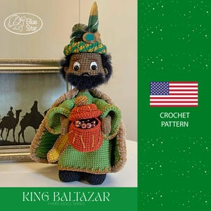 Peut inclure: Poupée crochetée du roi Balthazar de la série des Rois Mages. La poupée porte une robe verte et marron, une lanterne rouge et un chapeau décoratif avec une plume. L'image comprend également le texte "CROCHET PATTERN" et le drapeau américain.