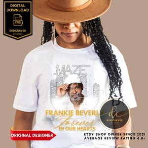 May include: White t-shirt with a black and white graphic design featuring a portrait of Frankie Beverly, the lead singer of the band Maze. The graphic design includes the text "MAZE" and "Frankie Beverly Forever In Our Hearts".