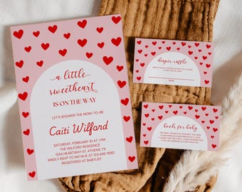 May include: Pink baby shower invitation with red hearts and the text "a little sweetheart is on the way". The invitation includes the name "Caiti Wilford" and details for the shower, including the date, time, location, and RSVP information.