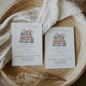 May include: Two pink and white bridal shower invitations with a stack of books tied with a pink ribbon and floral accents. The text on the invitations reads "her next chapter" and "Please join us for a Bridal Shower honoring Amber Johnson".
