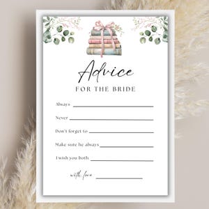 May include: A white card with the text "Advice FOR THE BRIDE" in elegant script. The card features a watercolor illustration of a stack of books tied with a pink ribbon, and space to write advice.