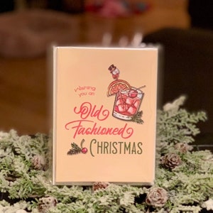 May include: A Christmas card with a vintage illustration of an old fashioned cocktail with a cherry and orange slice. The text reads "Wishing you an Old Fashioned Christmas".