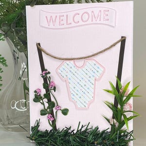 Baby shower.Nouveau bébé. Carte de voeux pour fille. Intérieur vierge pour votre message de bienvenue. Bruant sur la corde à linge avec des fleurs. Prêt à être expédié !