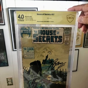 Puede incluir: Un cómic clasificado en una caja de plástico. El cómic se titula "House of Secrets" y presenta una ilustración en blanco y negro de un castillo con una figura espeluznante en frente. El cómic es el número 97 y está fechado en mayo de 1972. El cómic está clasificado con un 4.0 por CBCS.