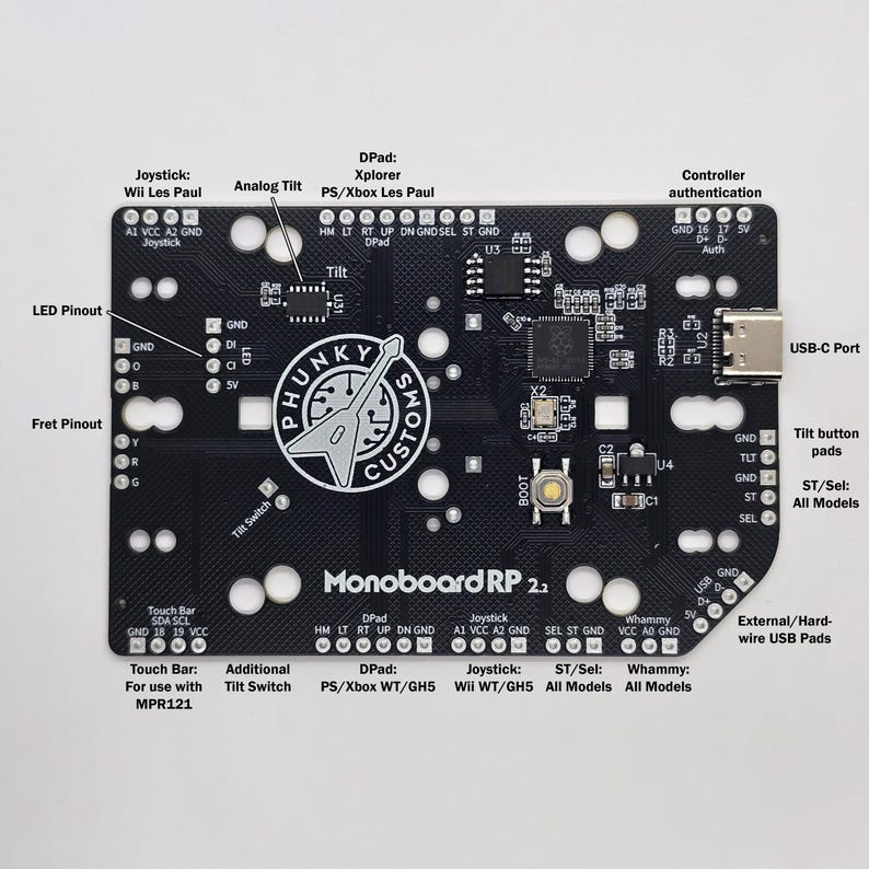 Puede incluir: Una placa de circuito impreso negra con el texto "Monoboard RP 2.2" impreso en ella. La placa tiene varios componentes, incluyendo un puerto USB-C, un interruptor de inclinaci&oacute;n, una barra t&aacute;ctil y un joystick. La placa est&aacute; dise&ntilde;ada para su uso con consolas de videojuegos.