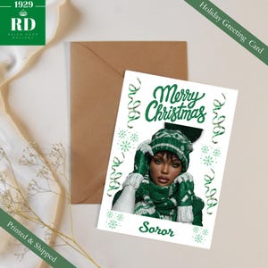 Peut inclure: Carte de vœux de Noël avec une femme portant un bonnet, une écharpe et des gants d'hiver verts et blancs. La carte indique "Joyeux Noël" en écriture verte, avec le mot "Soror" en dessous. Fond blanc avec des éléments verts.