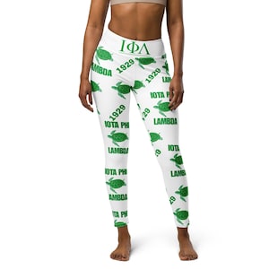 Op de afbeelding: Witte leggings met een groen-wit patroon van zeeschildpadden en de tekst "IOTA PHI 1929 LAMBDA".