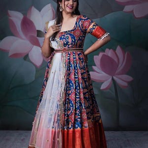 May include: A long, patterned dress in shades of blue, red, and gold. The dress features a detailed floral design, a fitted bodice, and a flowing skirt. The dress is paired with a white scarf and a decorative belt. The text "Only S Size" is in the top left corner.