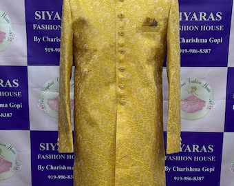 May include: A golden yellow, long-sleeved, formal jacket with a floral pattern. The jacket has a mandarin collar, a row of gold buttons, and a pocket square. The jacket is displayed on a mannequin.