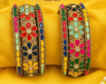 Puede incluir: Dos juegos de seis brazaletes multicolores de metal dorado con patrones florales en esmalte rojo, azul, amarillo, verde y rosa. Los brazaletes incluyen detalles de piedras claras y un diámetro interior indicado de 2.8 pulgadas.