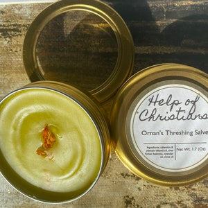 May include: A gold metal tin with a green salve inside. The tin has a label that reads "Help of Christians Ornan's Threshing Salve" and "Net Wt. 1.7 (Oz)".