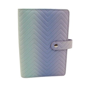 May include: A light blue and purple ombre planner with a chevron pattern and a snap closure.