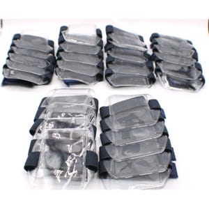 May include: A collection of clear plastic arm guards with black elastic straps. The guards are rectangular and appear to be stacked in several groups, suggesting a bulk purchase or supply of protective gear.