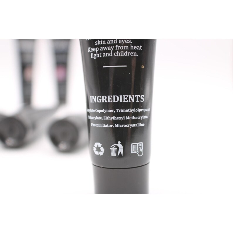 May include: A black tube of nail product with the word "INGREDIENTS" printed in white. The ingredients list includes "Acrylate Copolymer" and "Trimethylolpropane". The tube also has recycling symbols and text that reads "Keep away from heat light and children."