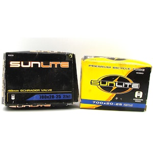 May include: Two Sunlite bicycle inner tube boxes. One is black with white and orange text, including "48mm Schrader Valve" and "700x20-25 27x1." The other is yellow with black text, labeled "Premium Bicycle Tube" and "700x20-25 27x1."