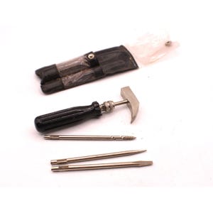 May include: A vintage multi-tool set with a black handle, hammer head, and various screwdriver bits. The set includes a black leatherette case. The tools are made of metal and appear to be in good condition.