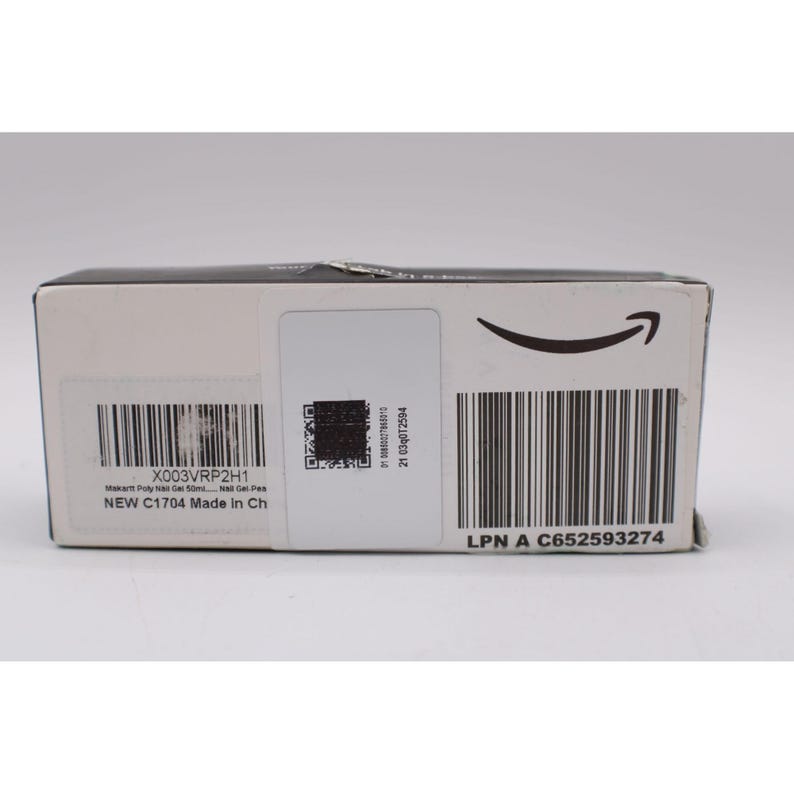 Op de afbeelding: Een rechthoekige doos met de tekst "X003VRP2H1" en "Makart Poly Nail Gel 50ml... Nail Gel-Pen". De doos heeft ook een barcode, een QR-code en de tekst "NEW C1704 Made in Ch". De doos heeft het Amazon-logo.