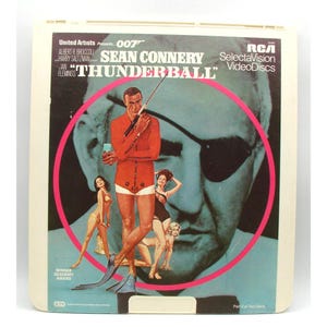May include: Vintage RCA SelectaVision VideoDisc of the James Bond film "Thunderball" starring Sean Connery. The cover features a movie poster design with a pink circle, images of Bond and women, and the film's title.