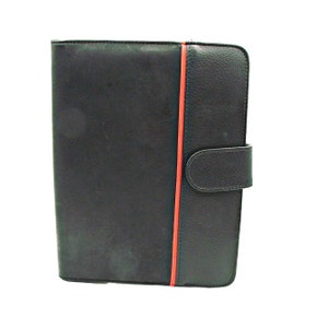 May include: Black leather folder with a red stripe down the center and a flap closure.