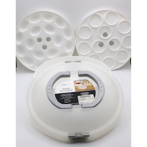 May include: A white plastic round 3-in-1 food carrier with a gray handle and two removable interior trays. The label reads Round 3-in-1 Carrier, Easy to carry & helps keep food fresh, Snap tight lid, Easy grip handle, Dishwasher safe, 11.6 in dia x 4.7 in (29.5 cm x 11.9 cm).