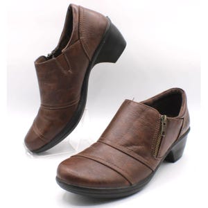 May include: A pair of brown leather ankle boots with a low heel. The boots have a side zipper and a rounded toe. The heel height is approximately 2 inches.