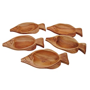 May include: Five wooden fish-shaped bowls. Each bowl is carved from a light brown wood, featuring a detailed fish design with a head, body, and tail fin. The bowls have a shallow, rounded interior, perfect for serving snacks or small dishes.