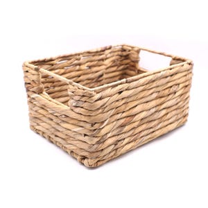 May include: A rectangular woven basket with built-in handles. The basket is made of natural-colored woven material. The basket is designed for storage and organization.