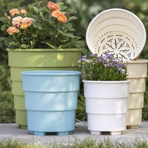 May include: A collection of colorful, tiered plastic planters in various sizes. The planters are in shades of green, blue, white, and cream, some holding flowers. The design features a series of horizontal bands, and the planters sit on small feet.
