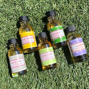 May include: Five small glass bottles with black caps containing essential oils. The bottles are labeled with the names of the oils: "White Sage", "Spiritual Healing", "Lemon Grass", "Patchouli", and "Lavender".