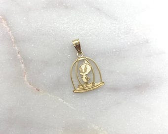 May include: A gold pendant featuring a cutout design of a small bird character standing inside a rounded cage structure. The pendant has a polished finish and includes a small bail at the top for attachment to a chain or necklace accessory.