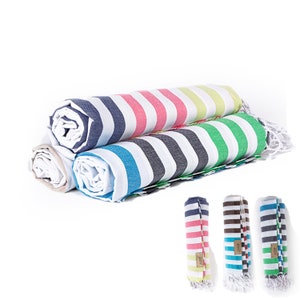 May include: Three rolled up striped towels in different color combinations. The towels are white with stripes of pink, green, blue, and yellow. The towels are rolled up and have fringe on the ends.