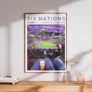 Könnte beinhalten: Ein Poster in lila und blauen Farben, das eine Stadionmenge zeigt, die ein Rugby-Spiel verfolgt. Das Poster lautet "Six Nations Rugby Frankreich-Schottland 2025".