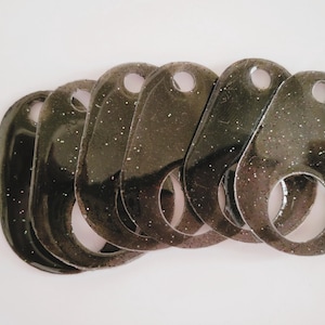 Könnte beinhalten: Ein Satz mit sieben schwarzen, glitzernden Schlüsselanhängern aus Kunststoff mit einem Ring an jedem Anhänger.