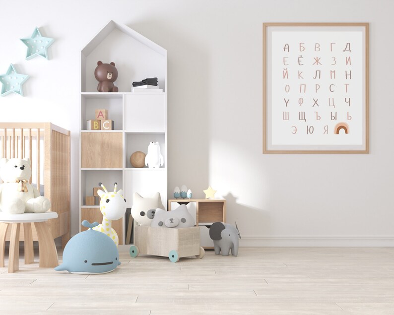 May include: A white nursery with a crib, a wooden bookshelf with a brown bear, a giraffe, and a whale toy, a wooden toy chest with a cat toy, and a framed poster with the Cyrillic alphabet and a rainbow.