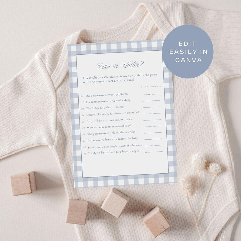 May include: A baby shower game card with a blue and white gingham border, titled "Over or Under?" The card is on a white onesie, with wooden blocks and dried flowers nearby. The text includes questions about the parents-to-be.