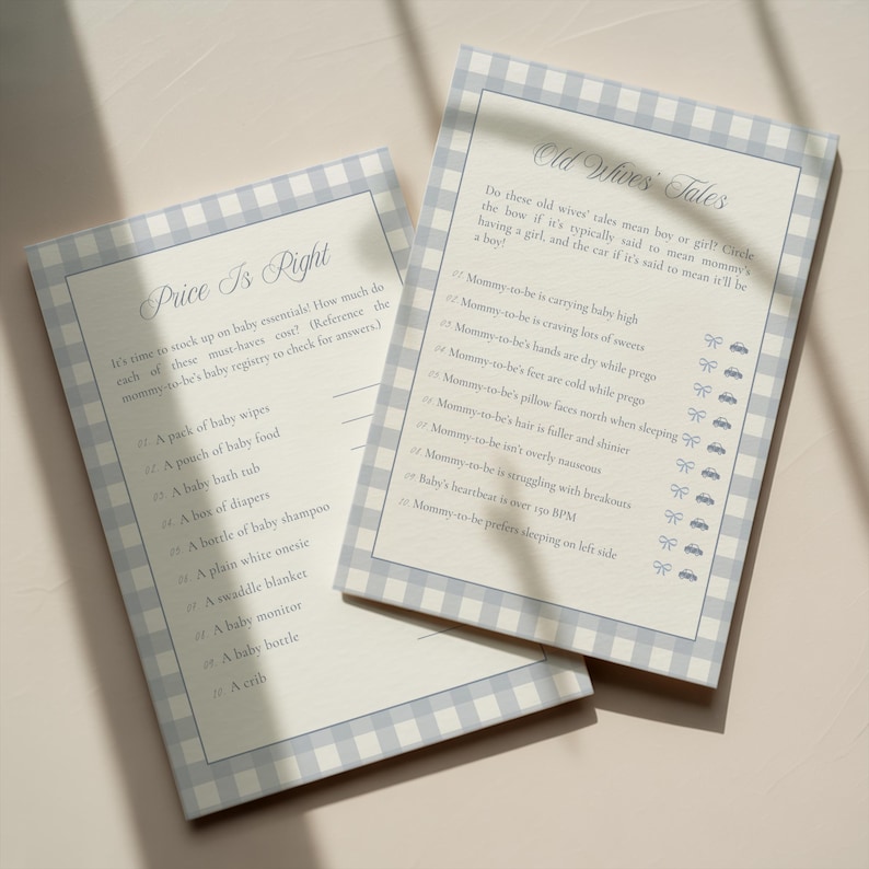 May include: Two baby shower game cards with a blue and white gingham border. One card is titled "Price Is Right" and lists baby essentials. The other card is titled "Old Wives' Tales" and lists gender prediction clues.