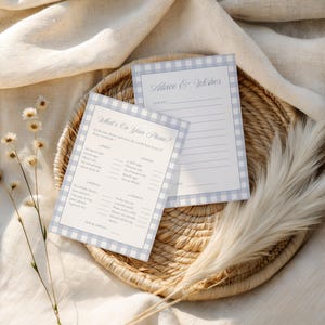May include: Two light blue and white gingham patterned game cards on a woven basket. One card reads "What's On Your Phone?" and the other reads "Advice & Wishes". The cards are for a bridal shower or baby shower.