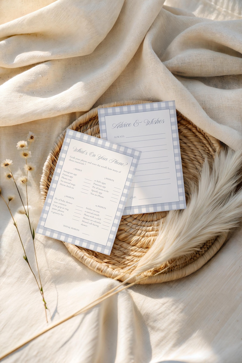 May include: Two light blue and white gingham patterned game cards on a woven basket. One card reads "What's On Your Phone?" and the other reads "Advice & Wishes". The cards are for a bridal shower or baby shower.